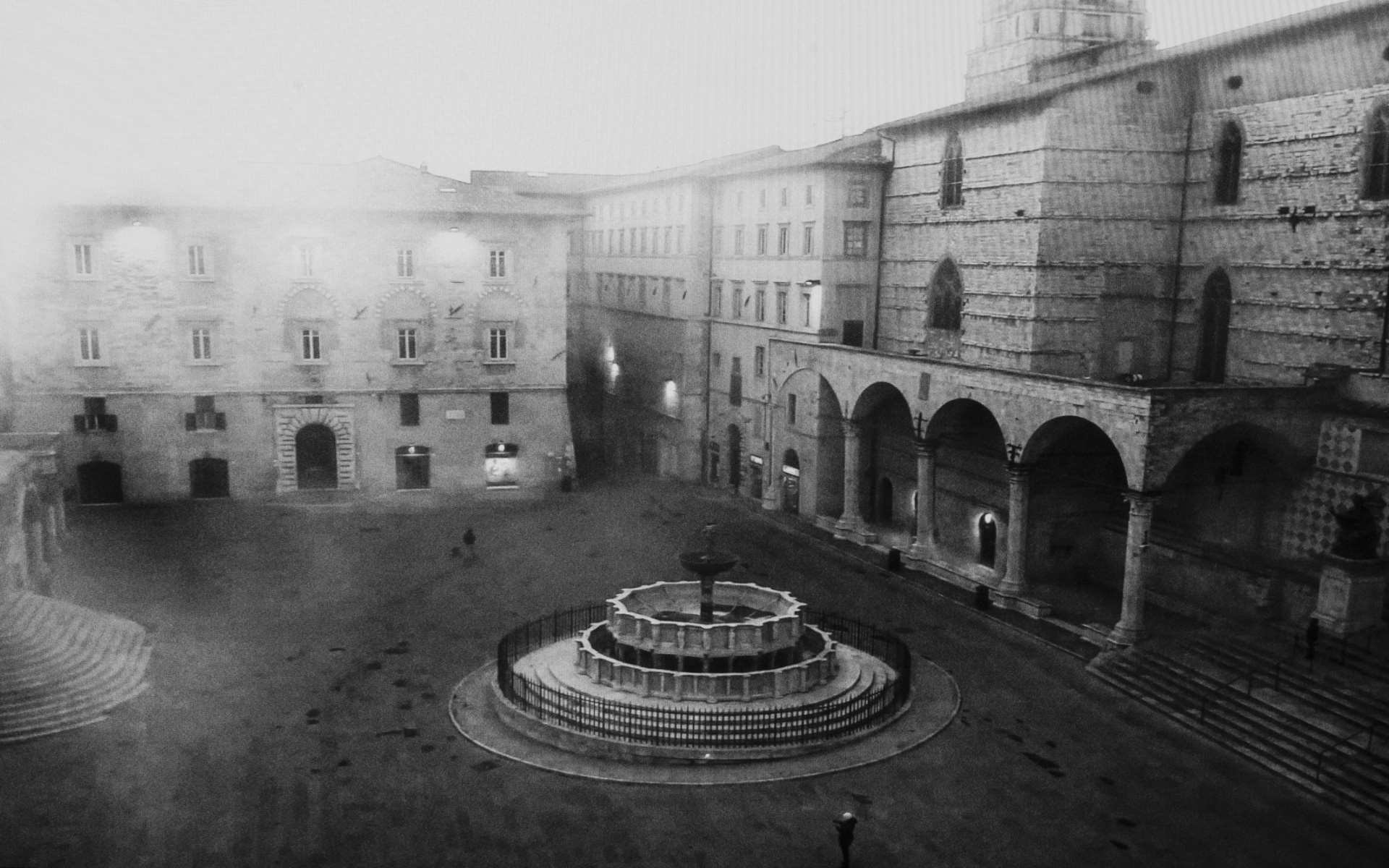 Perugia, Square of the 4th November - Man navigating his drone, seen as white dot, on an empty square to take a top-down photograph of Magiorre fountain. Perugia, Italy. March 25. 2020